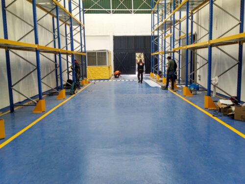 Piso de poliuretano azul con demarcación amarilla aplicado por GSA Ingeniería en bodega en Bogotá