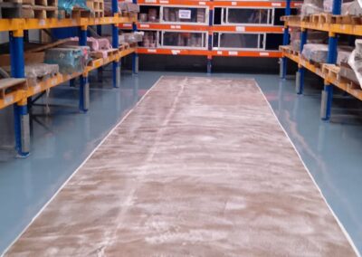 Vista panorámica de pasillo entre estanterías con piso epóxico multicapa instalado por GSA Ingeniería