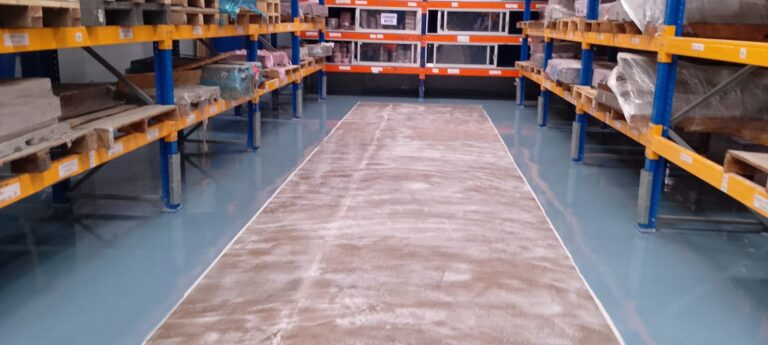 Vista panorámica de pasillo entre estanterías con piso epóxico multicapa instalado por GSA Ingeniería