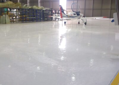 Piso epóxico Sikafloor-264 con demarcación amarilla en hangar de avionetas, obra de GSA Ingeniería