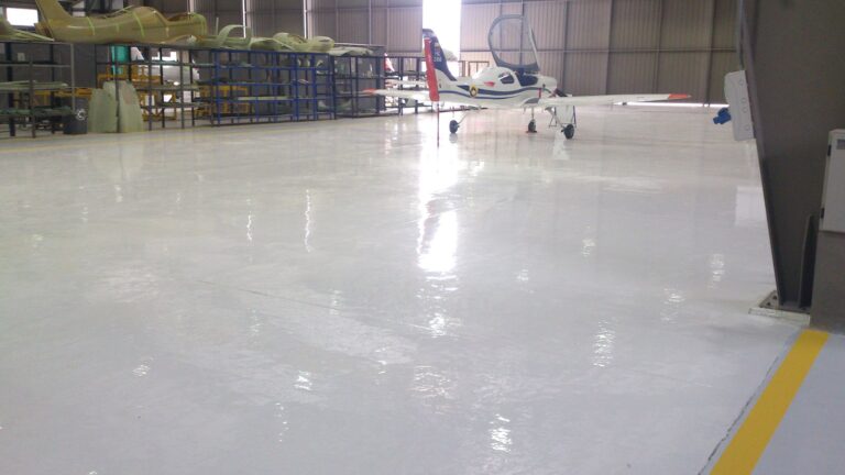 Piso epóxico Sikafloor-264 con demarcación amarilla en hangar de avionetas, obra de GSA Ingeniería