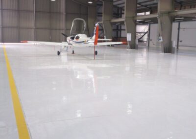 Avioneta sobre piso epóxico Sikafloor-264 con línea de demarcación en hangar de Bogotá, GSA Ingeniería
