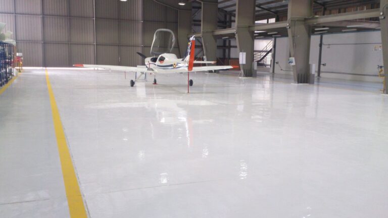 Avioneta sobre piso epóxico Sikafloor-264 con línea de demarcación en hangar de Bogotá, GSA Ingeniería