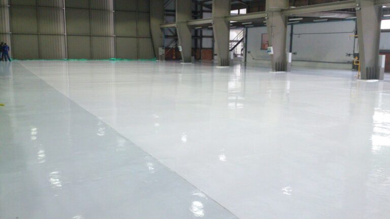 Detalle del acabado brillante de piso epóxico Sikafloor-264 en hangar, GSA Ingeniería