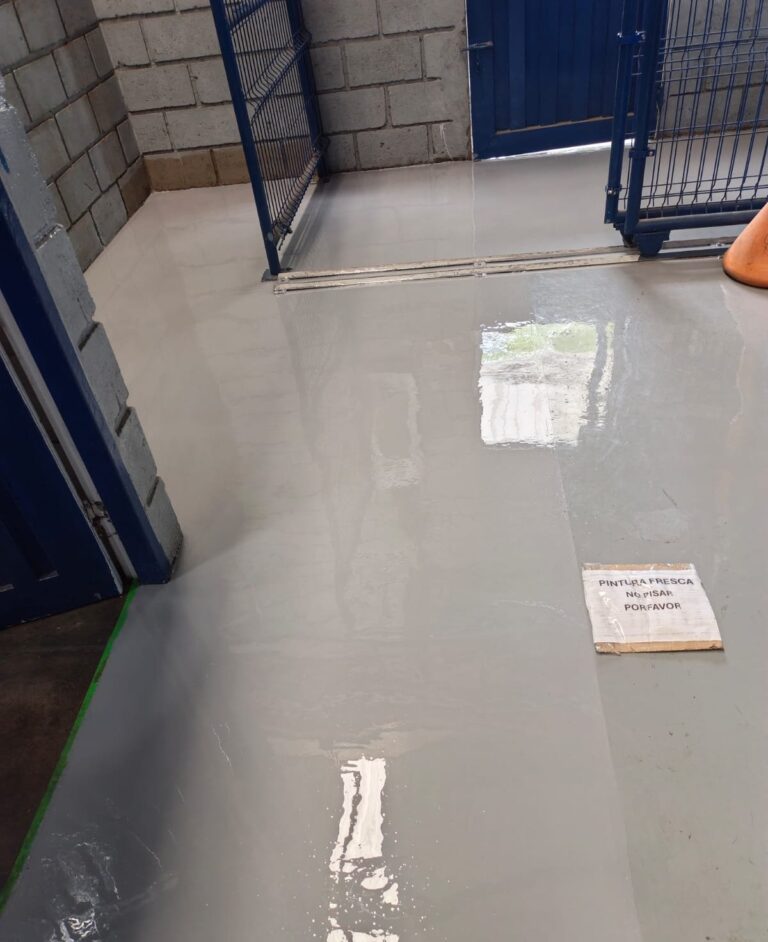 Piso epóxico multicapa gris brillante en cuarto de almacenamiento con divisiones en malla, aplicado por GSA Ingeniería