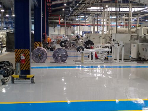 Pasillo de montacargas con piso epóxico multicapa gris y franjas azul y amarilla aplicado por GSA Ingeniería