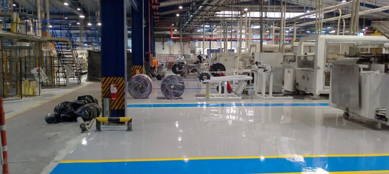 Pasillo de montacargas con piso epóxico multicapa gris y franjas azul y amarilla aplicado por GSA Ingeniería