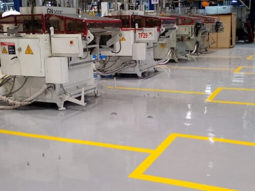 Pasillo con piso epóxico multicapa gris y demarcación amarilla y azul aplicado por GSA Ingeniería en planta industrial