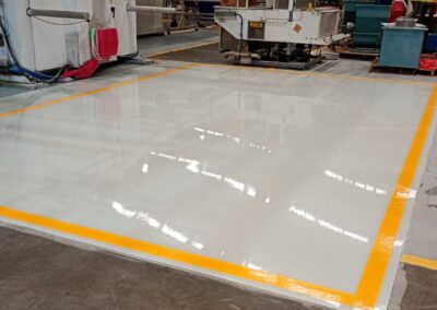 Área amplia de piso conductivo antiestático con borde amarillo en planta de fabricación, obra de GSA Ingeniería