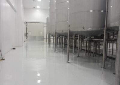 Piso epóxico sanitario terminado por GSA Ingeniería en zona de tanques de planta de alimentos
