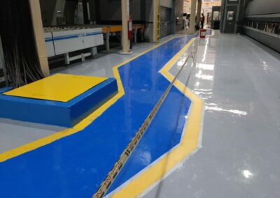 Detalle de demarcación amarilla y azul de pasillos sobre piso epóxico aplicado por GSA Ingeniería